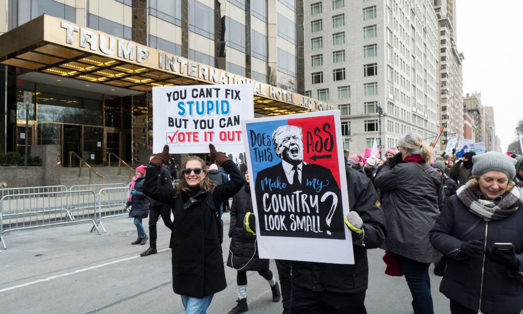 People hold up signs protesting against president Donald Trump, who has been taken off the Colorado primary ballot after a ruling by the state's supreme court