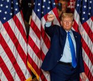 This picture shows Donald Trump standing against three American flags holding a raised fist to supporters.