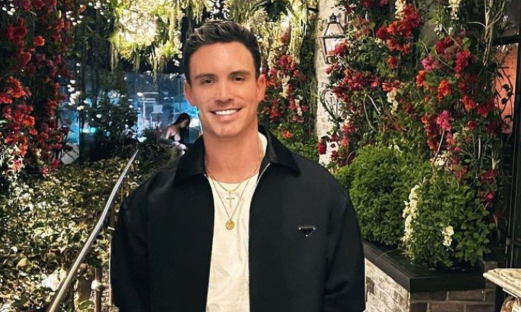 Gay model and influencer Jeff Thomas, who is among the LGBTQ+ celebs who died in 2023, wears a white shirt and black jacket while he smiles and poses for a photo outdoors