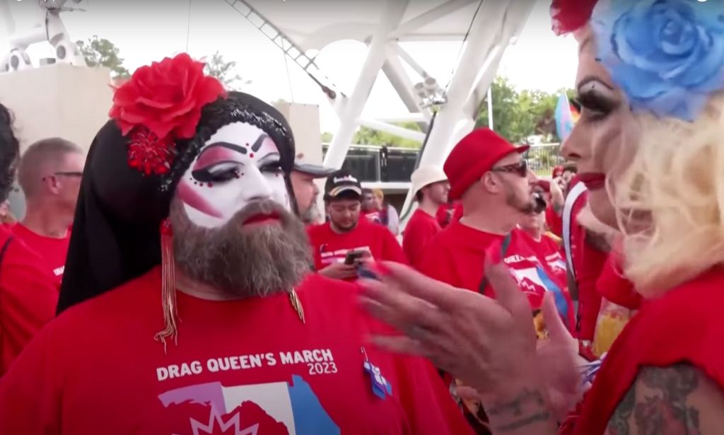 A group of drag performers wear makeup and red shirts as they march in an LGBTQ+ protest in Florida, USA