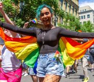 A person wears a rainbow coloured cape as they walk in an LGBTQ+ pride celebration in the US state of Oregon