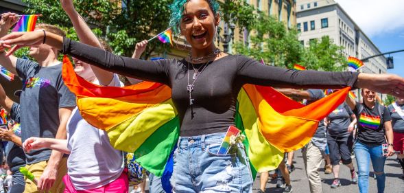 A person wears a rainbow coloured cape as they walk in an LGBTQ+ pride celebration in the US state of Oregon