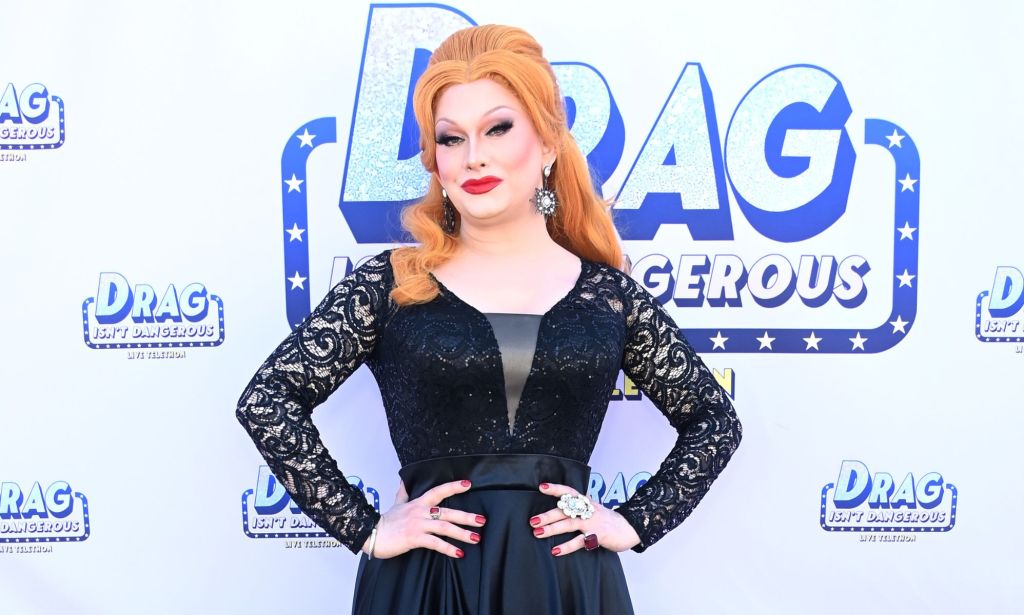 Drag Race superstar Jinkx Monsoon poses while wearing a black and grey dress
