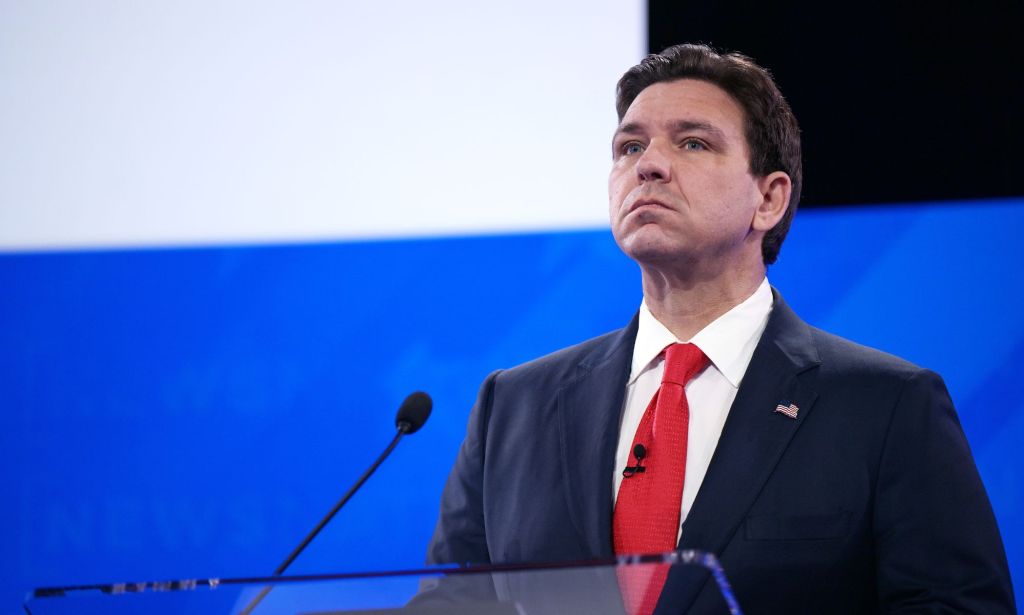 GOP presidential hopeful Ron DeSantis wears a suit and tie as he stands at a podium for the Republican debate, where he made several anti-trans statements