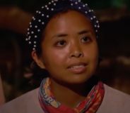 A screenshot from Survivor 41 of contestant Erika Casupanan wearing a light coloured shirt and dark headband with pearls on it