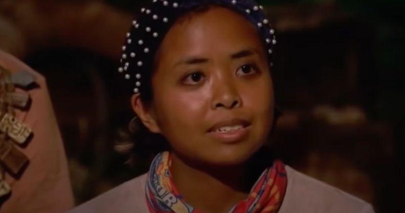 A screenshot from Survivor 41 of contestant Erika Casupanan wearing a light coloured shirt and dark headband with pearls on it
