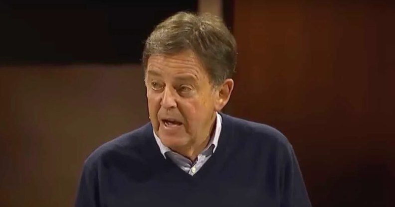 Christian pastor dropped by radio network, Alistair Begg, addresses the crowd from a stage in his sermon on Sunday (28 January) he is an older man wearing a dark blue sweater over a buttoned up shirt.