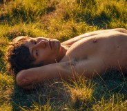 Barry Keoghan as Oliver in Saltburn, he's topless lying in the grass