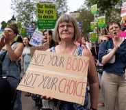 A protester stands with a pro-choice placard supporting legal abortion. The placard reads "not your body, not your choice"