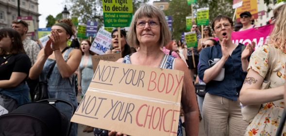 A protester stands with a pro-choice placard supporting legal abortion. The placard reads "not your body, not your choice"