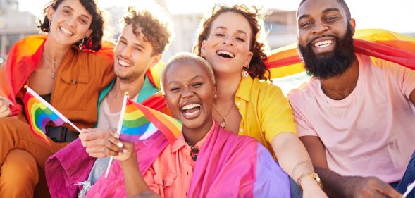 Stock image of a group of Gen Z friends all holding LGBTQ+ Pride flags