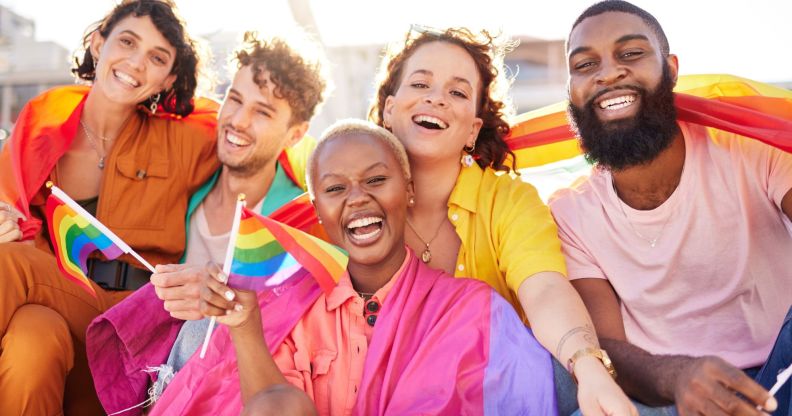 Stock image of a group of Gen Z friends all holding LGBTQ+ Pride flags