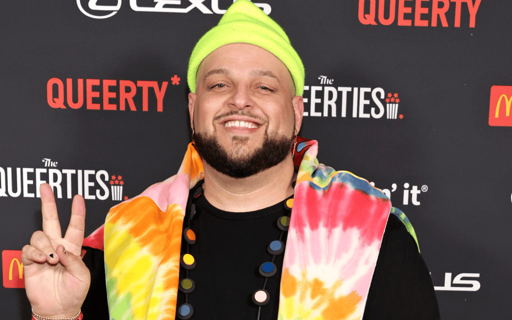 Mean Girls star Daniel Franzese posing on a red carpet holding up the peace sign.