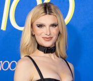 Dylan Mulvaney with blonde hair, wearing a black choker and strap top.