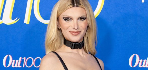 Dylan Mulvaney with blonde hair, wearing a black choker and strap top.