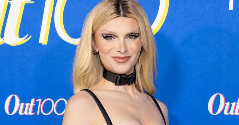 Dylan Mulvaney with blonde hair, wearing a black choker and strap top.