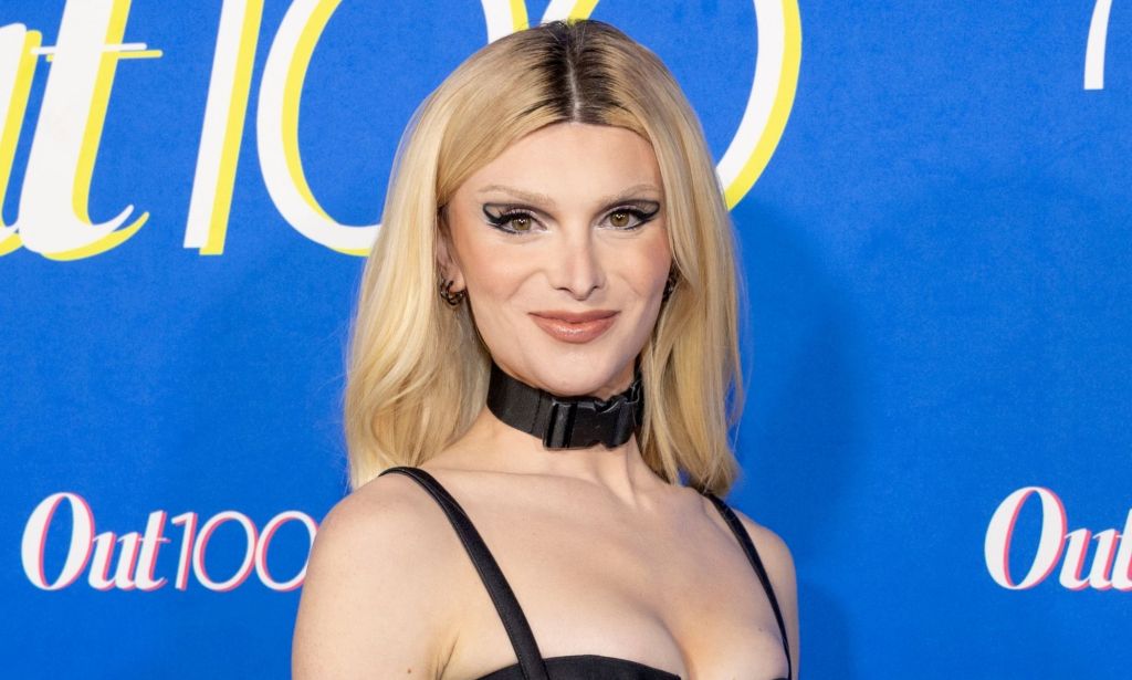 Dylan Mulvaney with blonde hair, wearing a black choker and strap top.