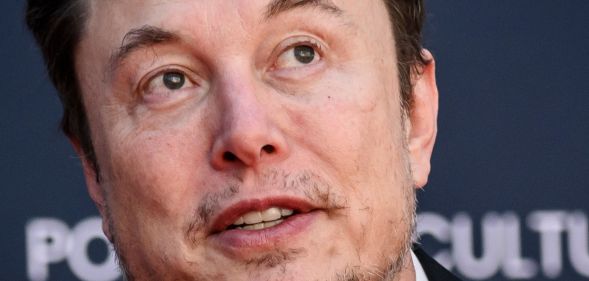 Elon Musk, looking upwards while speaking at an event.