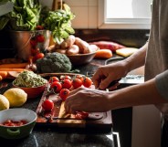 Human hands slicing tomatoes over a wooden table for a vegan meal