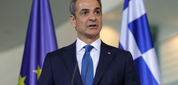 Kyriakos Mitsotakis infront of a Greece and European Union flag.