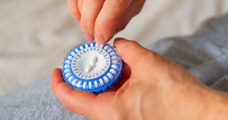 A person picks a pill out of a HRT capsule.