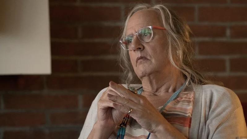Jeffrey Tambor as trans charcter Maura in Transparent. Maura is an older woman, wearing glasses, a grey cardigan and red striped top.