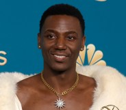 Poor Things star Jerrod Carmichael wearing a fur throw with his chest showing and holding an emmy