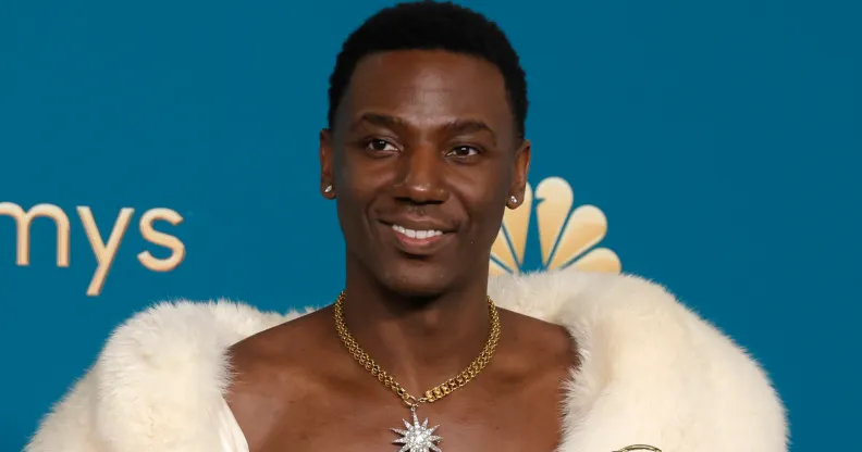 Poor Things star Jerrod Carmichael wearing a fur throw with his chest showing and holding an emmy