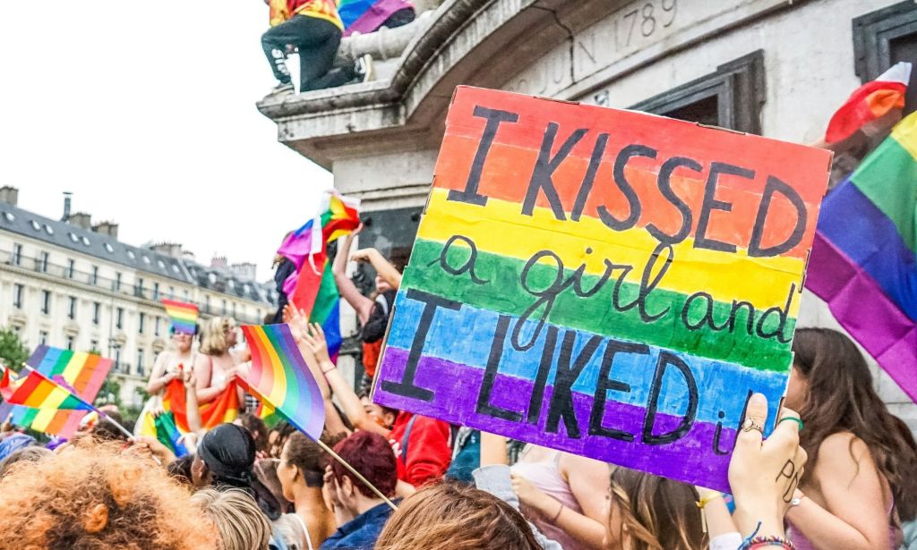 People at a protect with a poster held up high saying 'I Kissed A Girl and I Liked It'