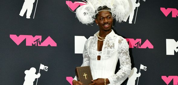 Lil Nas X poses with a bible in the press room at the 2023 MTV Video Music Awards