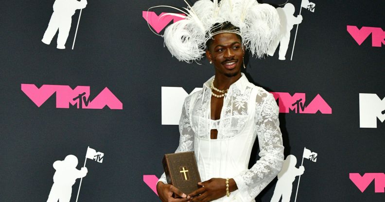 Lil Nas X poses with a bible in the press room at the 2023 MTV Video Music Awards