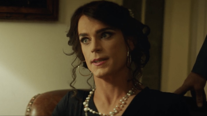 Matt Bomer plays trans character Freda in Anything, Freda has dark hair up, hoop earings and a pearl necklace.