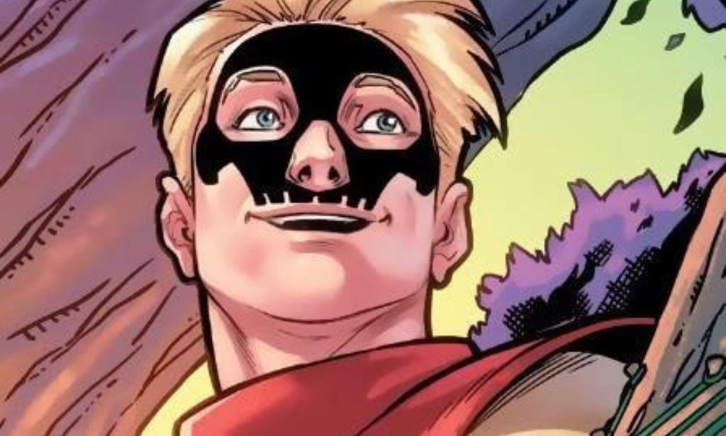 A blonde man with a skull tattoo on his face smiles.