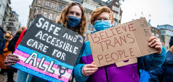 Two people hold placards in support of trans healthcare during a protest in Amsterdam on 6 February 2022