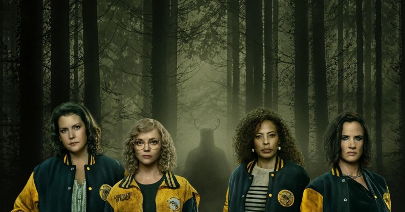 The cast of Yellowjackets in the woodland with a silhouette with horns behind them.