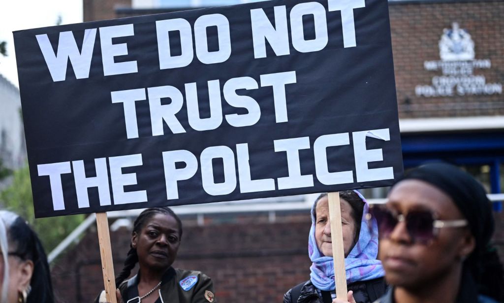Protestors hold up a sign that reads "we do not trust the police"