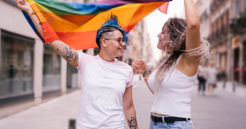 two women holding a pride flag and looking at each other romantically