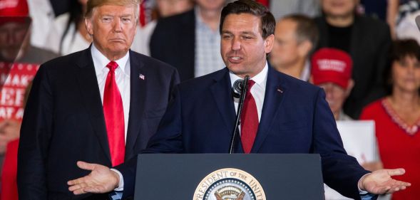Ron DeSantis stands at a podium next to former president Donald Trump