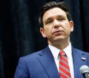 A picture of Florida governor Ron DeSantis, who signed a controversial book ban law, wears a suit and tie as he speaks into a microphone
