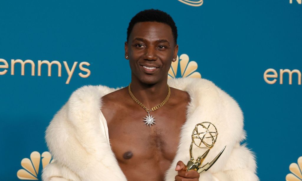 Jerrod Carmichael wearing a fur throw with his chest showing and holding an emmy