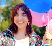 Kris Tyson, a YouTuber and MrBeast collaborator who is trans, smiles as she holds up pink and blue balloons next to her