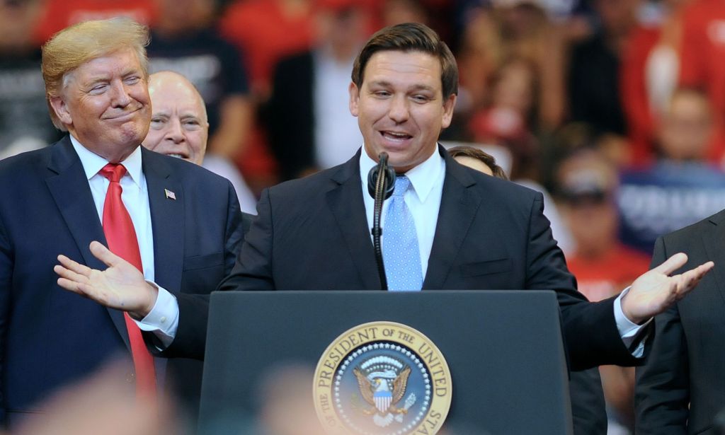 Florida governor Ron DeSantis, who once was a top candidate in the 2024 Republican presidential race, stands at a podium next to former president Donald Trump