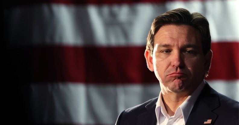 Florida governor Ron DeSantis, who once was a top candidate in the 2024 Republican presidential race, has a forlorn expression on his face as he stands in front of the red and white stripes of the US flag