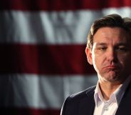Florida governor Ron DeSantis, who once was a top candidate in the 2024 Republican presidential race, has a forlorn expression on his face as he stands in front of the red and white stripes of the US flag