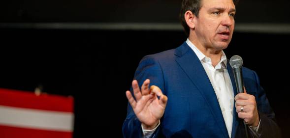 Florida governor wears a shirt and suit jacket while talking to people off screen