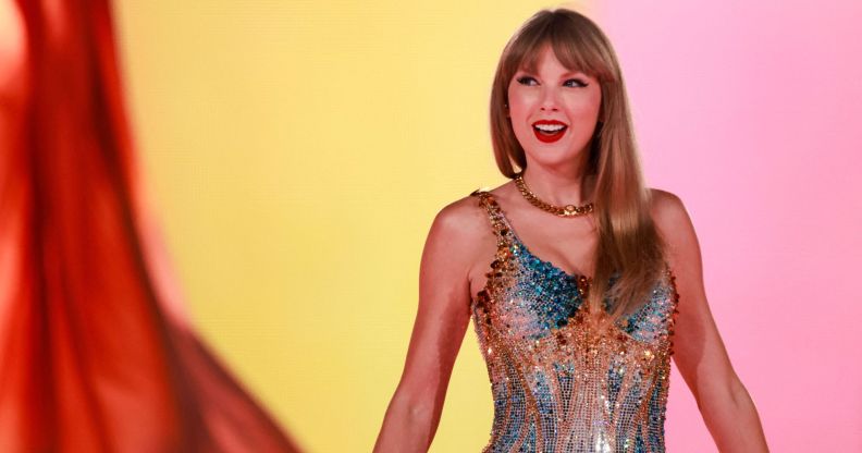 Taylor Swift wears a sparkly outfit as she poses with her arms out during a concert