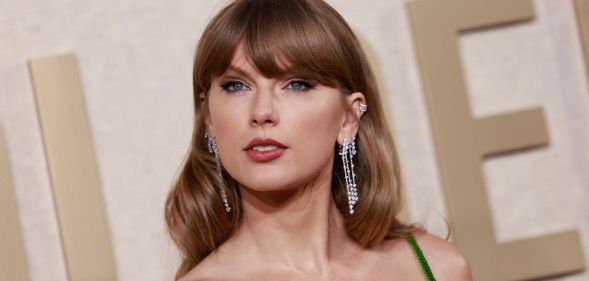 Taylor Swift looks towards the camera while wearing a green dress and long silver dangling earrings