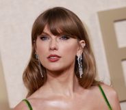 Taylor Swift looks towards the camera while wearing a green dress and long silver dangling earrings
