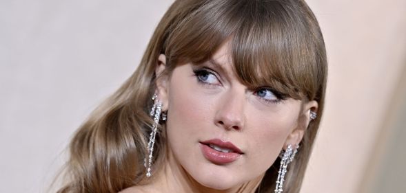 Taylor Swift looks over her shoulder as she wears a green dress and silver dangling earrings at an event