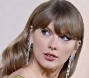 Taylor Swift looks over her shoulder as she wears a green dress and silver dangling earrings at an event